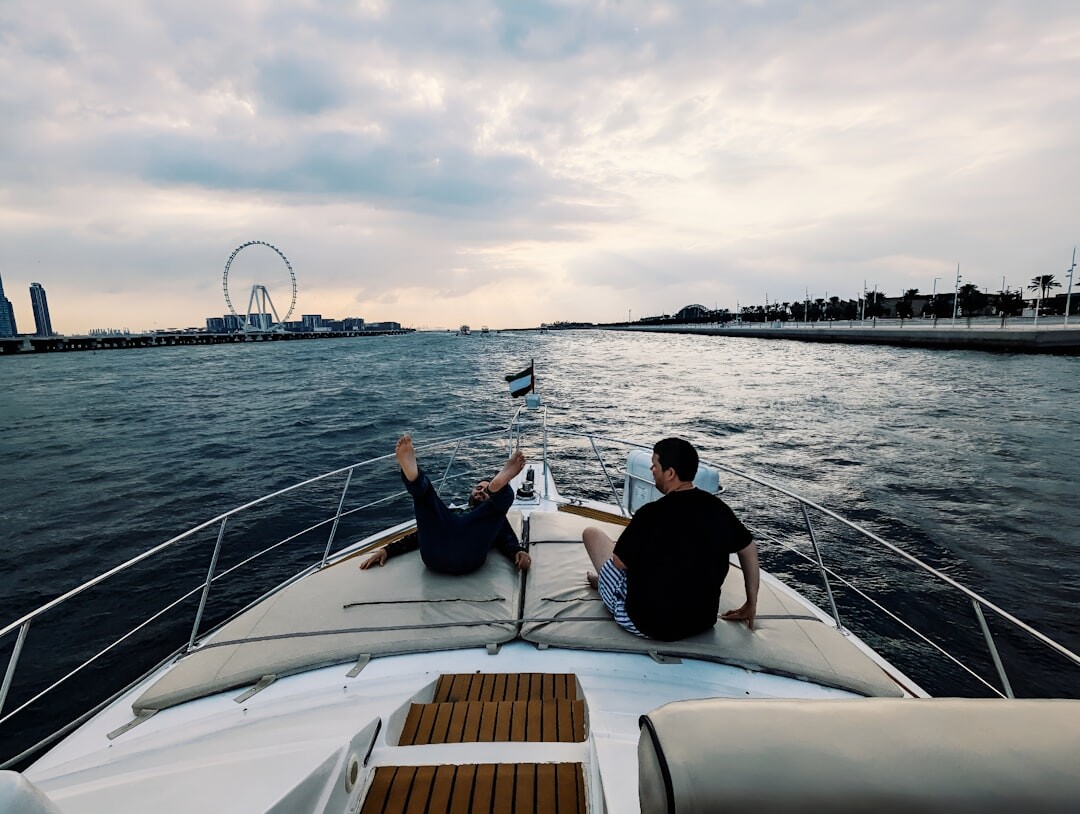 Man's wrist wearing a steel sports chronograph watch near a yacht railing